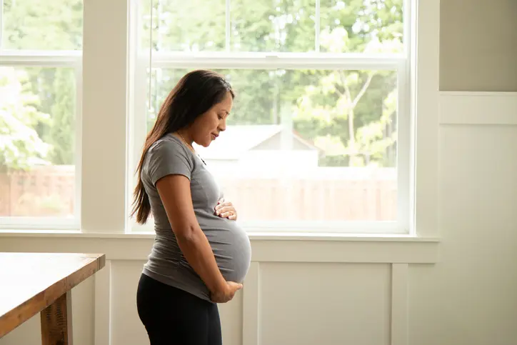 Young pregnant hispanic woman looking at her belly