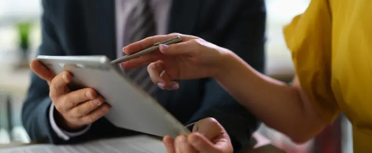 Two people, lawyer and client are discussing insurance information on tablet computer. Collaborate and discuss project on tablet