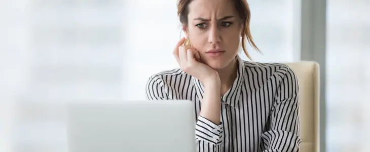 Confused businesswoman annoyed by online problem, spam email or fake internet news looking at laptop, female office worker feeling shocked about stuck computer, bewildered by scam message or virus